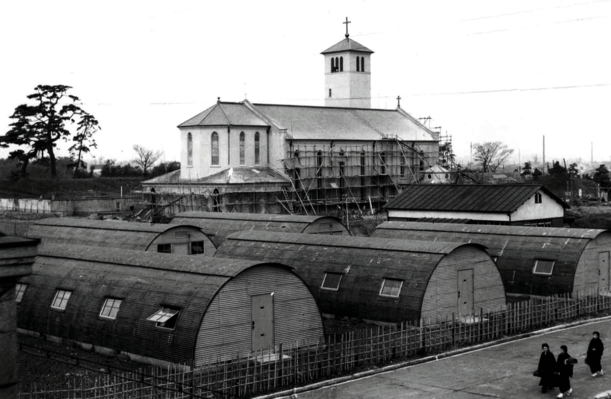 Quonset huts relocated on the Sophia campus, around the present location of Building No. 6. In the background is the old St. Ignatius Church, still under construction.